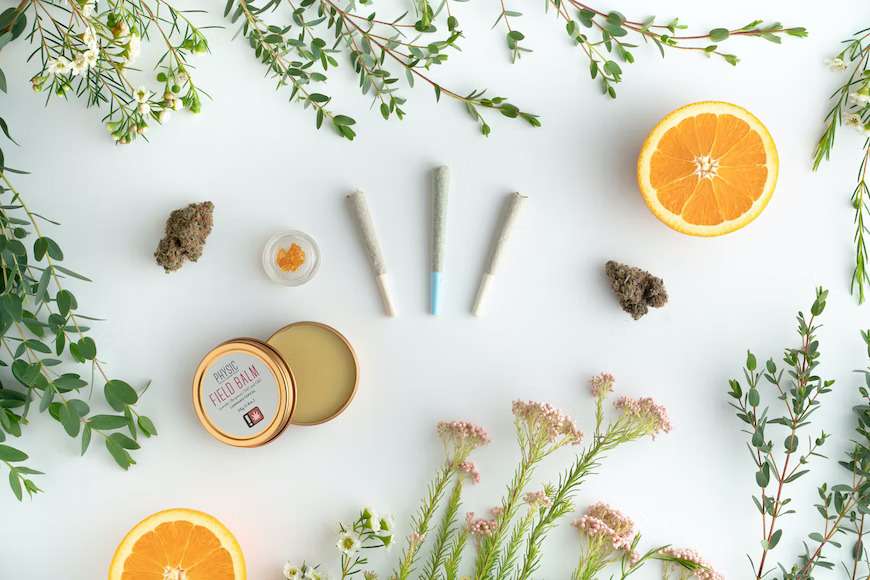 An assortment of cannabis products among botanicals such as oranges and flowers.